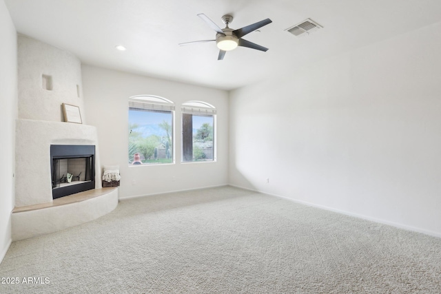 unfurnished living room featuring visible vents, baseboards, ceiling fan, carpet flooring, and a fireplace