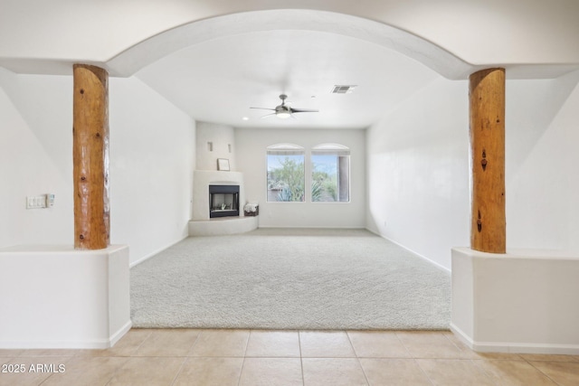 unfurnished living room with visible vents, light colored carpet, a large fireplace, and a ceiling fan