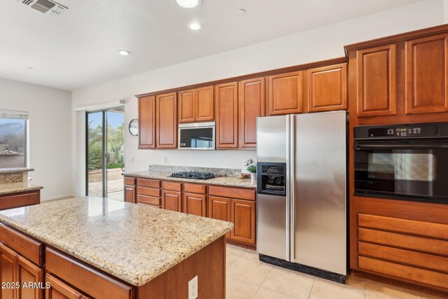 kitchen featuring black appliances, light stone counters, visible vents, and brown cabinets