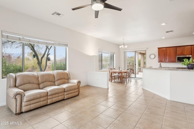 living area featuring light tile patterned floors, visible vents, ceiling fan with notable chandelier, and recessed lighting