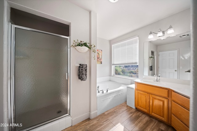 bathroom with plus walk in shower, wood-type flooring, and vanity