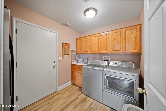 washroom with separate washer and dryer, cabinets, a textured ceiling, and light wood-type flooring