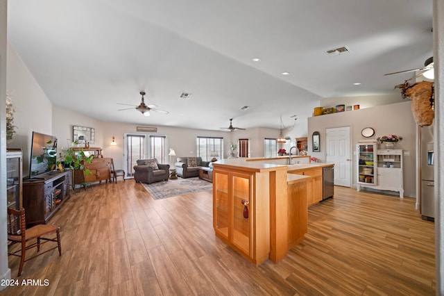 kitchen featuring sink, wood-type flooring, dishwasher, lofted ceiling, and an island with sink