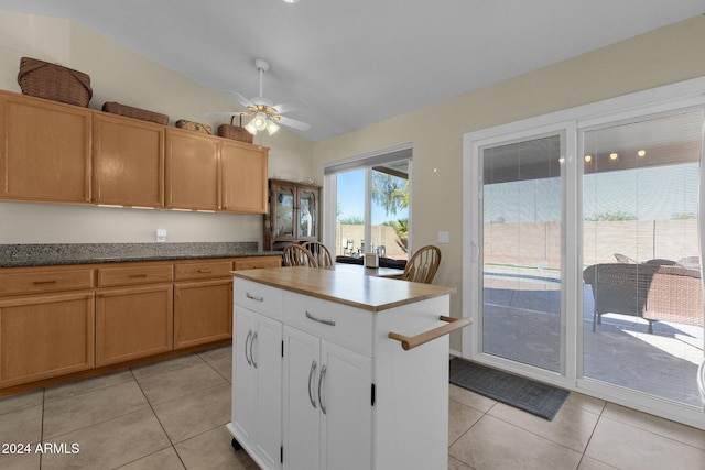 kitchen featuring ceiling fan, vaulted ceiling, a center island, white cabinetry, and light tile patterned floors