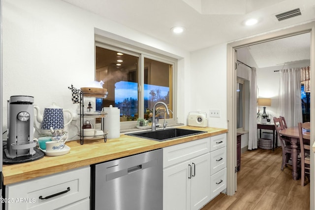 kitchen featuring butcher block countertops, a sink, visible vents, dishwasher, and light wood finished floors