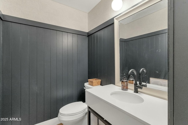 half bath featuring vanity, toilet, and wooden walls