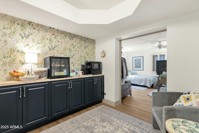 bar with wallpapered walls, light wood-style flooring, baseboards, and ceiling fan