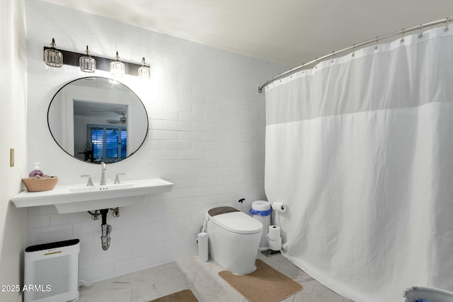 full bathroom featuring toilet, a shower with shower curtain, a sink, tile walls, and marble finish floor