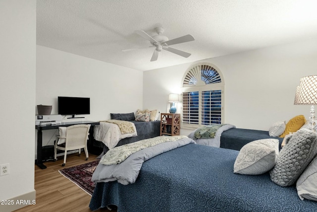 bedroom featuring ceiling fan, a textured ceiling, and wood finished floors