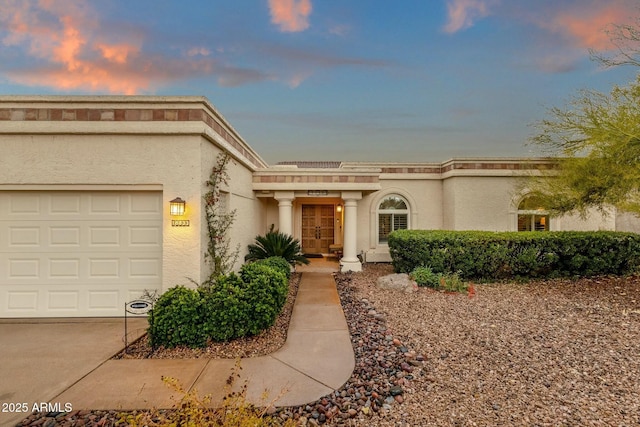 view of front of home featuring concrete driveway, an attached garage, and stucco siding