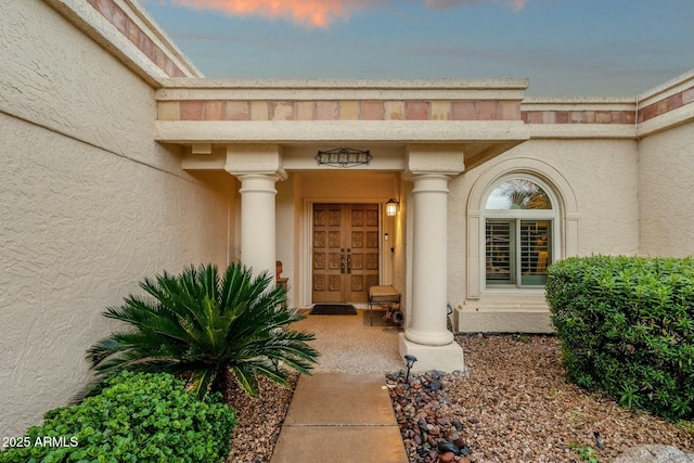 exterior entry at dusk with french doors and stucco siding