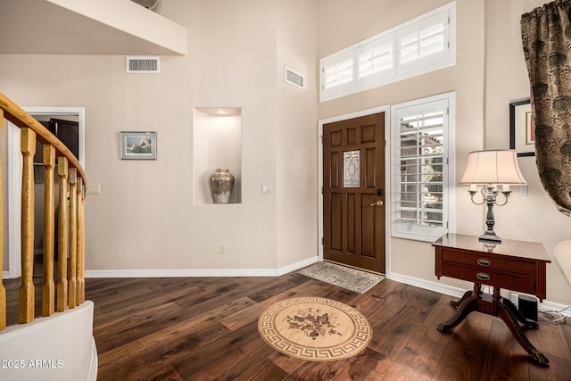 foyer entrance with stairs, wood-type flooring, visible vents, and baseboards