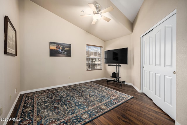 exercise room featuring a ceiling fan, vaulted ceiling, baseboards, and wood finished floors