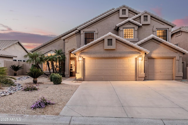 traditional home featuring an attached garage, concrete driveway, and stucco siding