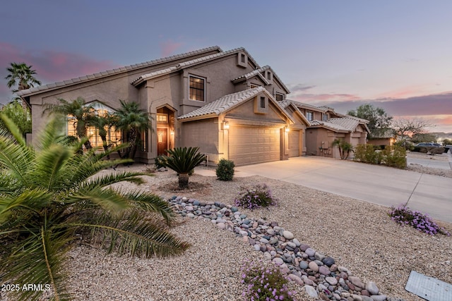 mediterranean / spanish-style home with a garage, concrete driveway, a tile roof, and stucco siding