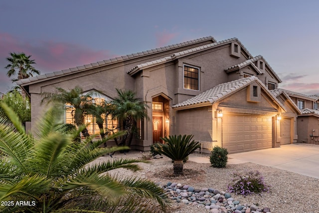 mediterranean / spanish house with concrete driveway, a tile roof, and stucco siding