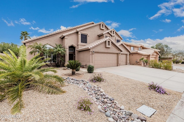 mediterranean / spanish-style home featuring a garage, concrete driveway, a tile roof, and stucco siding