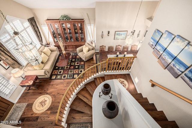 stairway with a notable chandelier, plenty of natural light, and wood finished floors