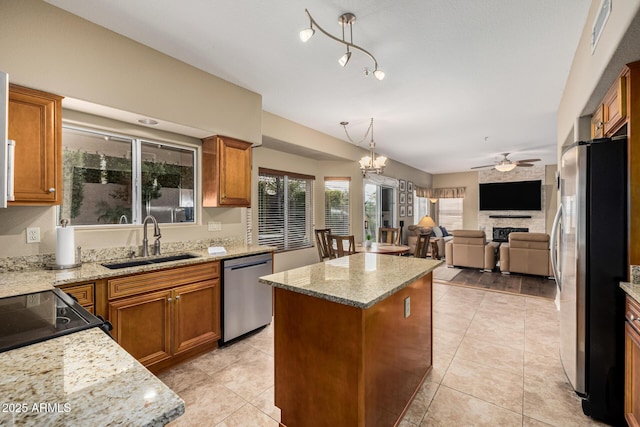 kitchen with brown cabinets, stainless steel appliances, a sink, and a center island