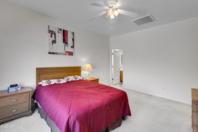 bedroom with ceiling fan, light colored carpet, and ensuite bath