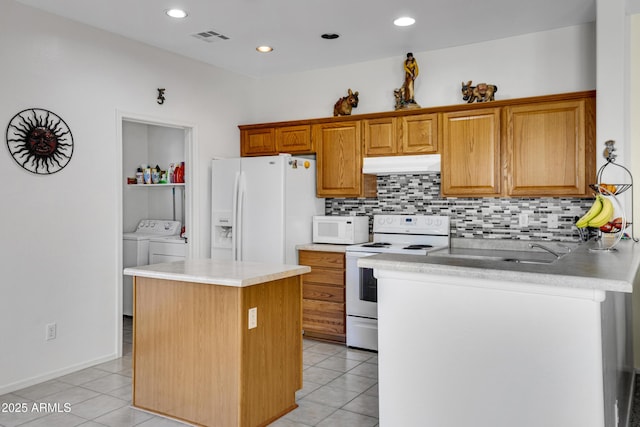 kitchen with a kitchen island, tasteful backsplash, light tile patterned floors, independent washer and dryer, and white appliances