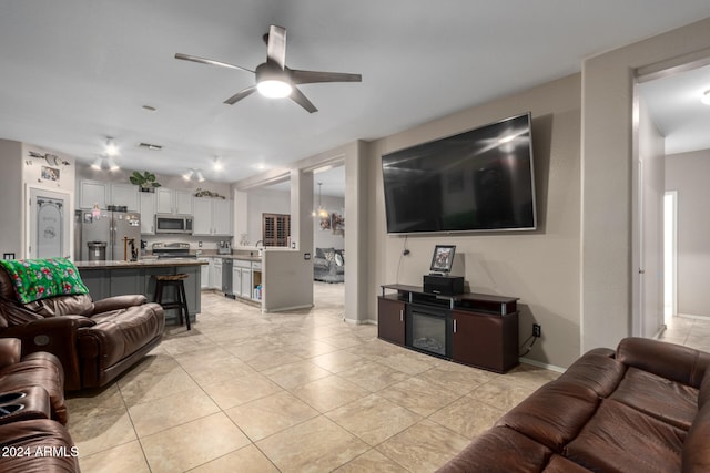 living room featuring ceiling fan with notable chandelier and light tile patterned flooring