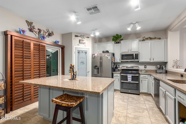 kitchen featuring light stone countertops, sink, a breakfast bar area, a kitchen island, and appliances with stainless steel finishes