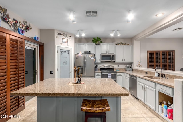 kitchen with a kitchen bar, a center island, stainless steel appliances, and sink