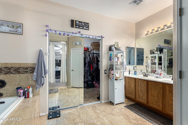 bathroom featuring tile patterned floors, vanity, and tiled tub