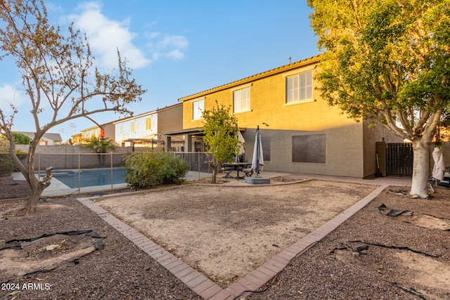 rear view of house with a fenced in pool and a patio area