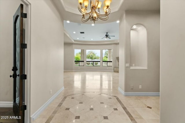 hall featuring an inviting chandelier and a raised ceiling