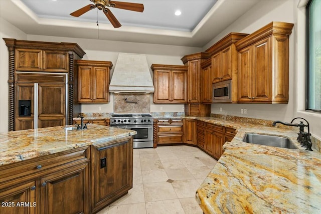 kitchen with premium range hood, stainless steel appliances, a tray ceiling, and sink