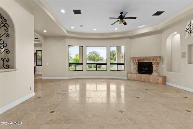 unfurnished living room featuring ceiling fan, light tile patterned flooring, a high end fireplace, and a tray ceiling