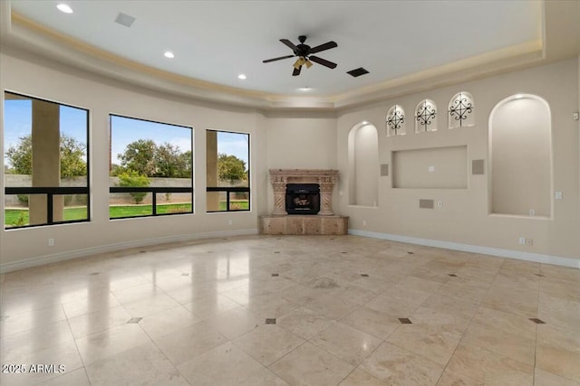 unfurnished living room with ceiling fan and a tray ceiling