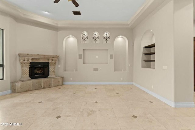 unfurnished living room with built in shelves and ceiling fan