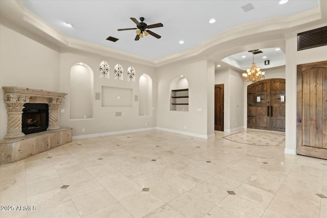 unfurnished living room with a tray ceiling and ceiling fan with notable chandelier