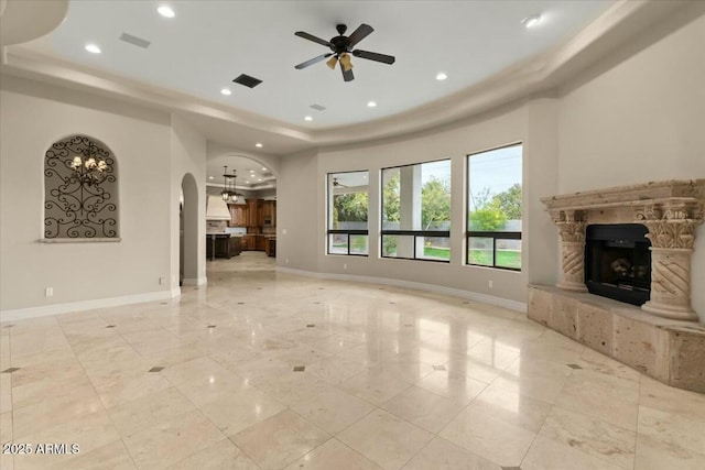 unfurnished living room featuring a raised ceiling and ceiling fan