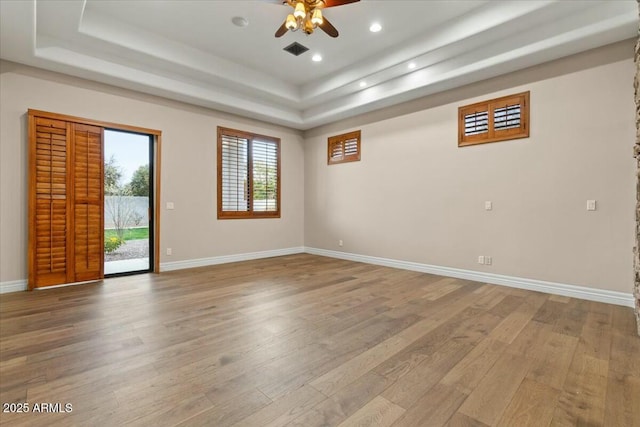 spare room featuring wood-type flooring, a raised ceiling, and ceiling fan