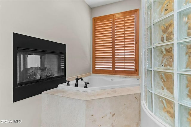 bathroom with tiled tub and a multi sided fireplace