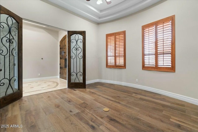 spare room with ceiling fan, wood-type flooring, and a tray ceiling