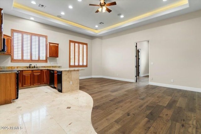 kitchen with ceiling fan, a tray ceiling, kitchen peninsula, and light hardwood / wood-style flooring