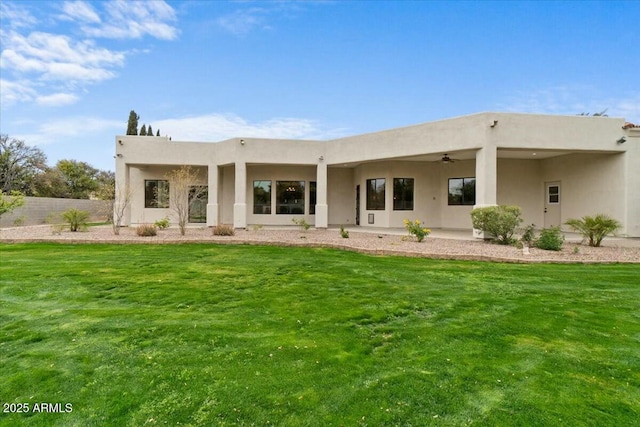 back of property featuring ceiling fan and a yard