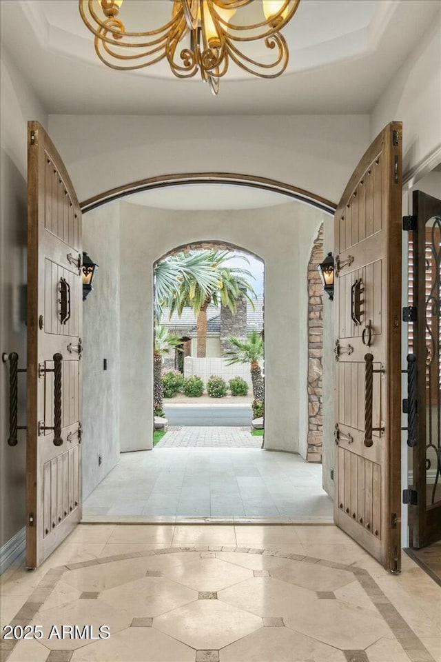 entryway featuring an inviting chandelier and a raised ceiling