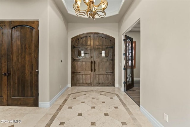 entrance foyer with an inviting chandelier and a raised ceiling