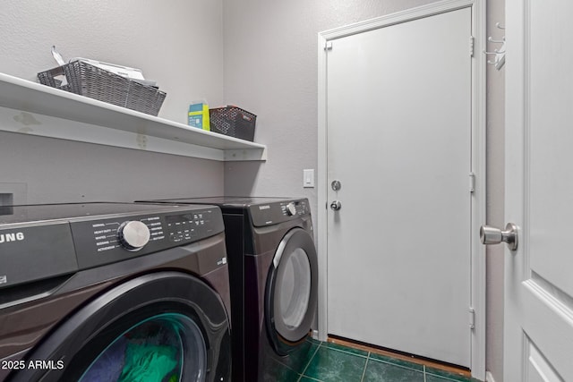 laundry area featuring dark tile patterned floors and washing machine and clothes dryer