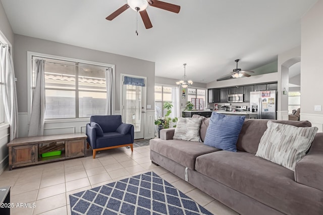 living room with ceiling fan with notable chandelier, lofted ceiling, and light tile patterned floors