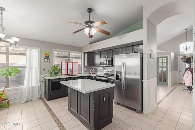 kitchen with stainless steel appliances, a kitchen island, lofted ceiling, and decorative light fixtures