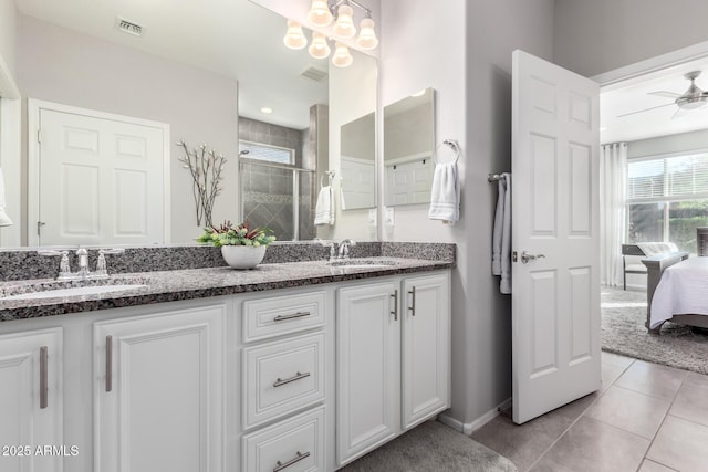 bathroom with tile patterned flooring, ceiling fan with notable chandelier, a shower with shower door, and vanity