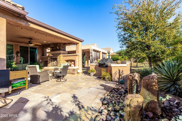 view of patio featuring an outdoor stone fireplace, area for grilling, and ceiling fan