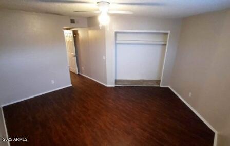 unfurnished bedroom featuring baseboards, a closet, a ceiling fan, and wood finished floors